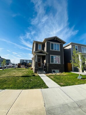 A two-story residential building with a front entrance, a driveway, and a well-maintained lawn. - Fabulous 4-bedroom house with 3 full bath l ACs in all rooms l Sleeps 8 plus  (Calgary)