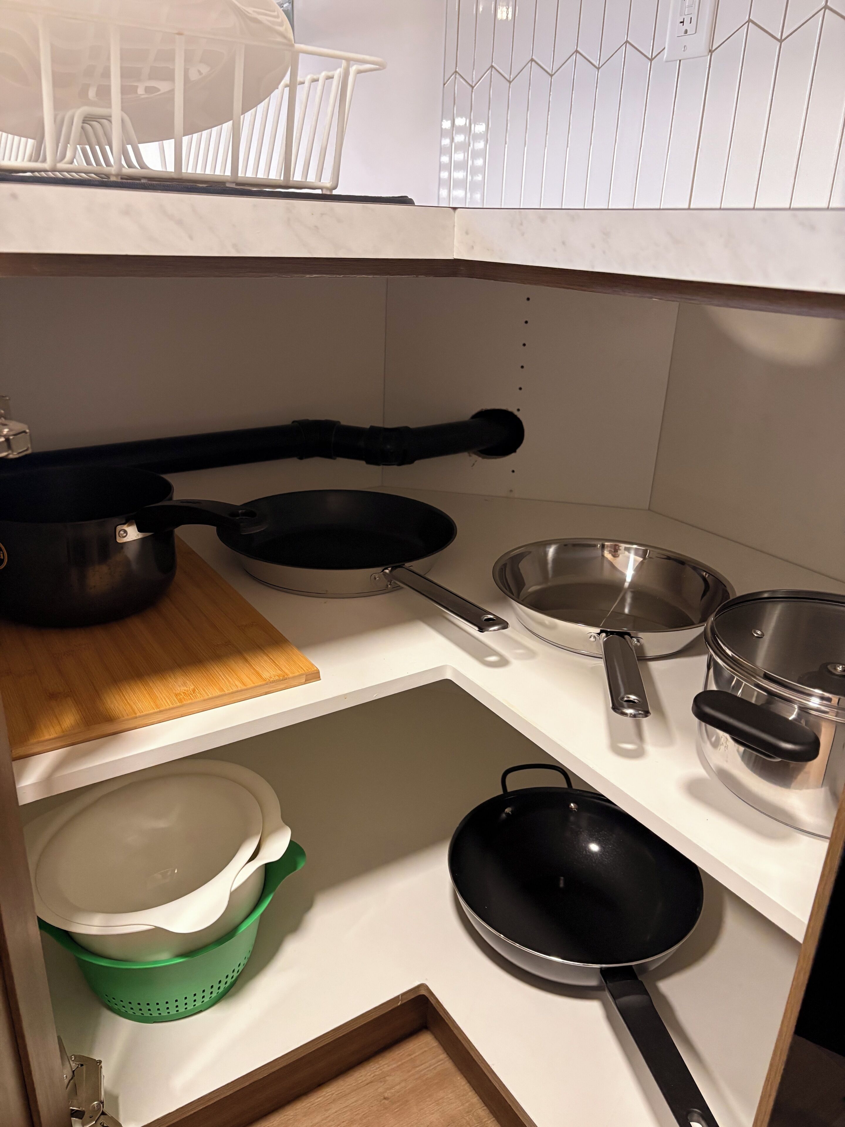 Een keuken met een houten aanrecht, diverse pannen en een groene zeef.