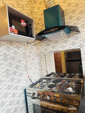 Une cuisine équipée d’une cuisinière à gaz, d’un four à micro-ondes et d’une hotte aspirante.