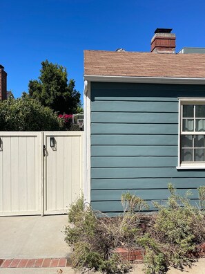 A residential building with a blue exterior, a white garage door, and a brick chimney. - Serenity Now Guest House (Los Angeles)