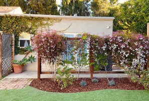 A garden with a wooden pergola, potted plants, and a brick pathway. - Serenity Now Guest House (Los Angeles)