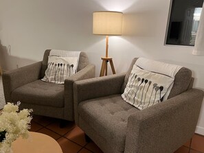Two armchairs with matching cushions, a floor lamp, and a small table with a vase of flowers. - Serenity Now Guest House (Los Angeles)