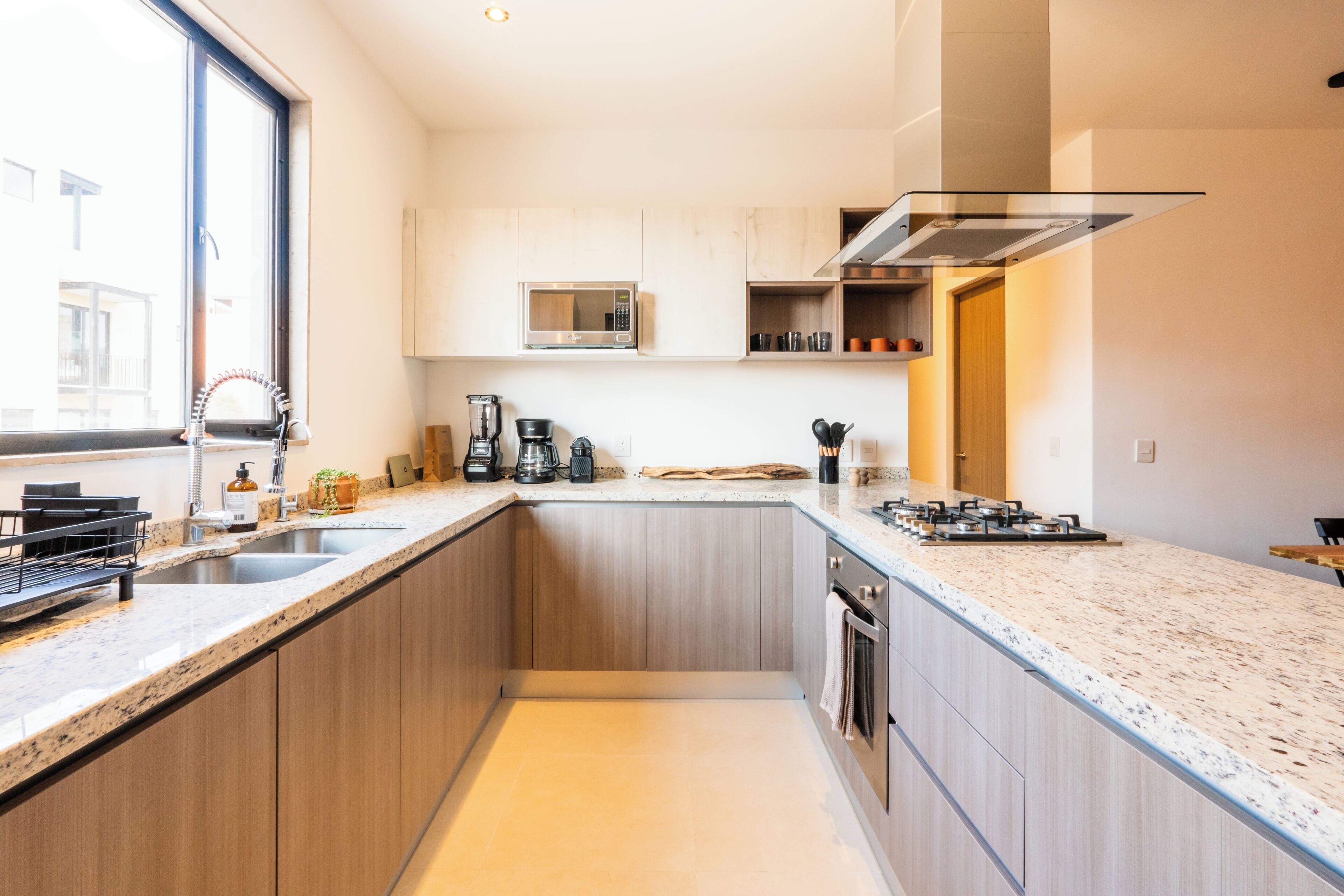 A modern kitchen with a large window, built-in appliances, and a central island.