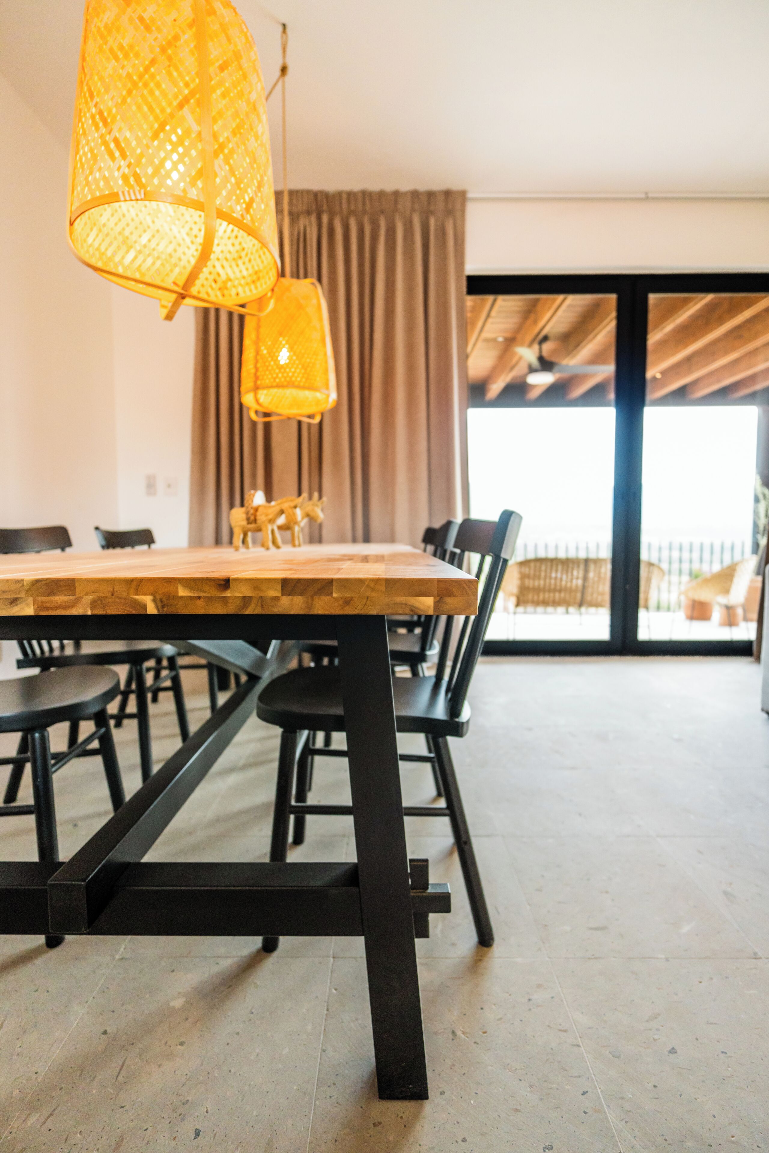 A dining area with a wooden table, black chairs, and a hanging light fixture.