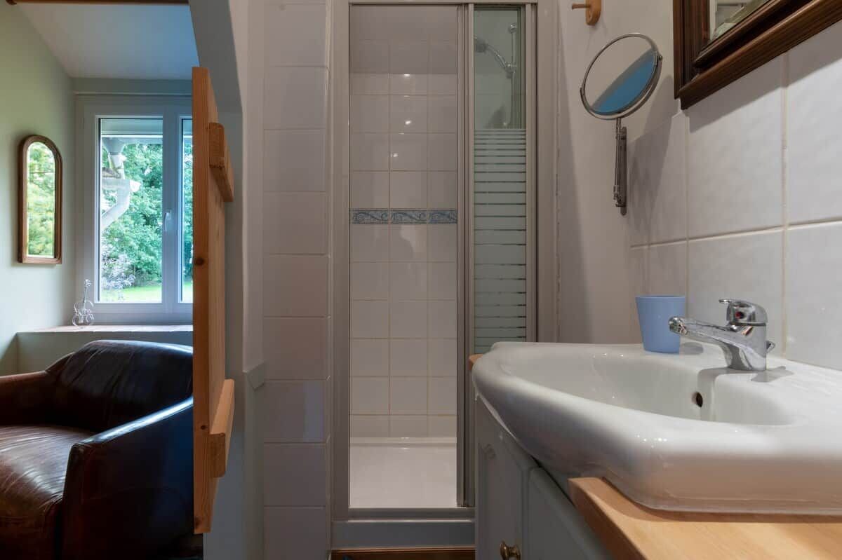 Une salle de bain avec une douche, un lavabo, un miroir et une fenêtre.