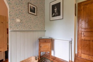 A room with a patterned wall, a wooden door, a radiator, and a small wooden table.