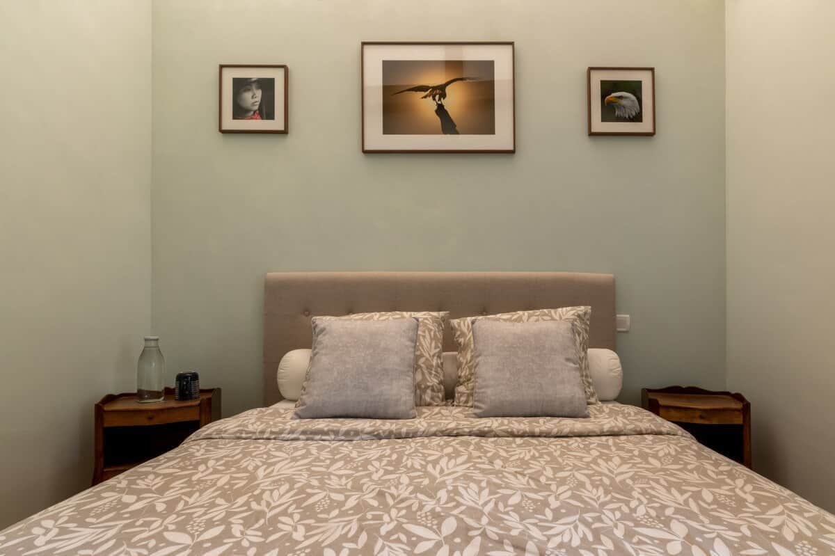 A bedroom with a bed, two nightstands, and three framed pictures on the wall.