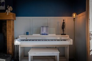 Un piano con un banco en una habitación con pared azul y una estatua sobre una estantería.
