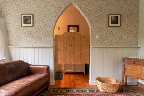 Ein Zimmer mit einem braunen Ledersofa, einem Holzschrank, einem gewebten Korb und einem gemusterten Teppich.