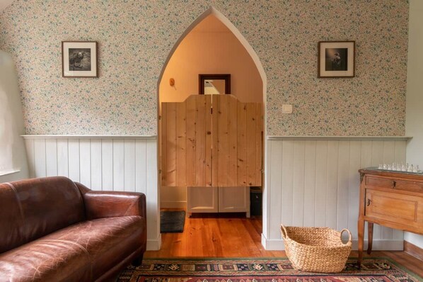 A room with a brown leather sofa, a wooden wardrobe, a woven basket, and a patterned rug.