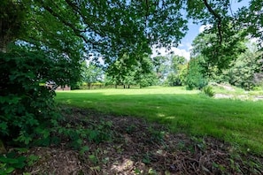 A well-maintained grassy area with trees and shrubs, likely a garden or park.