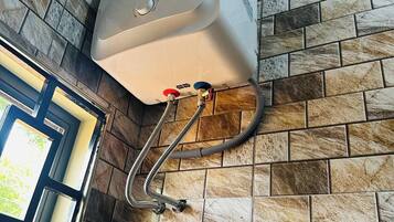 Un chauffe-eau fixé sur un mur recouvert de carreaux, avec une fenêtre sur le côté gauche.