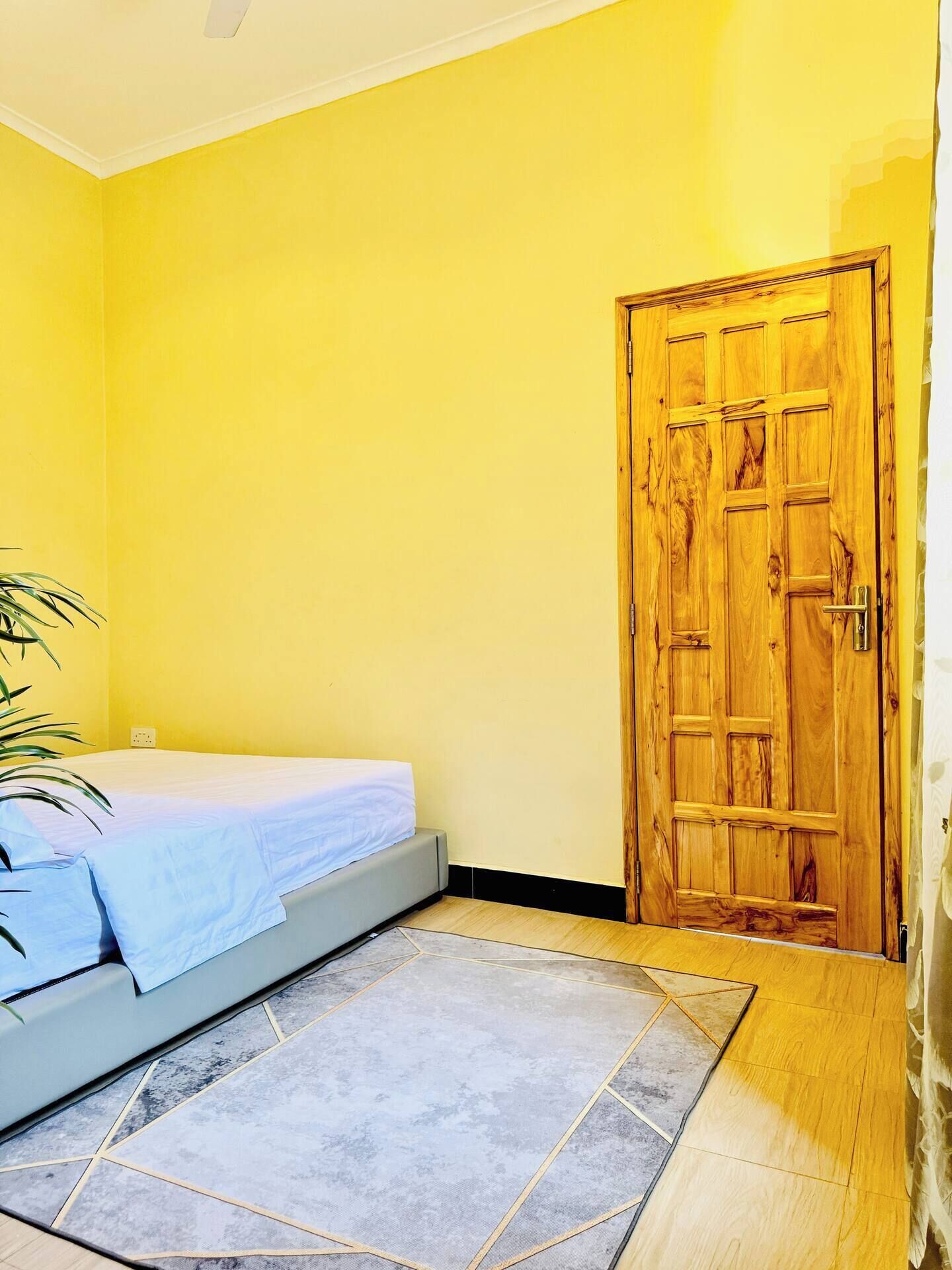 Une pièce avec un lit, une porte en bois et un sol carrelé.