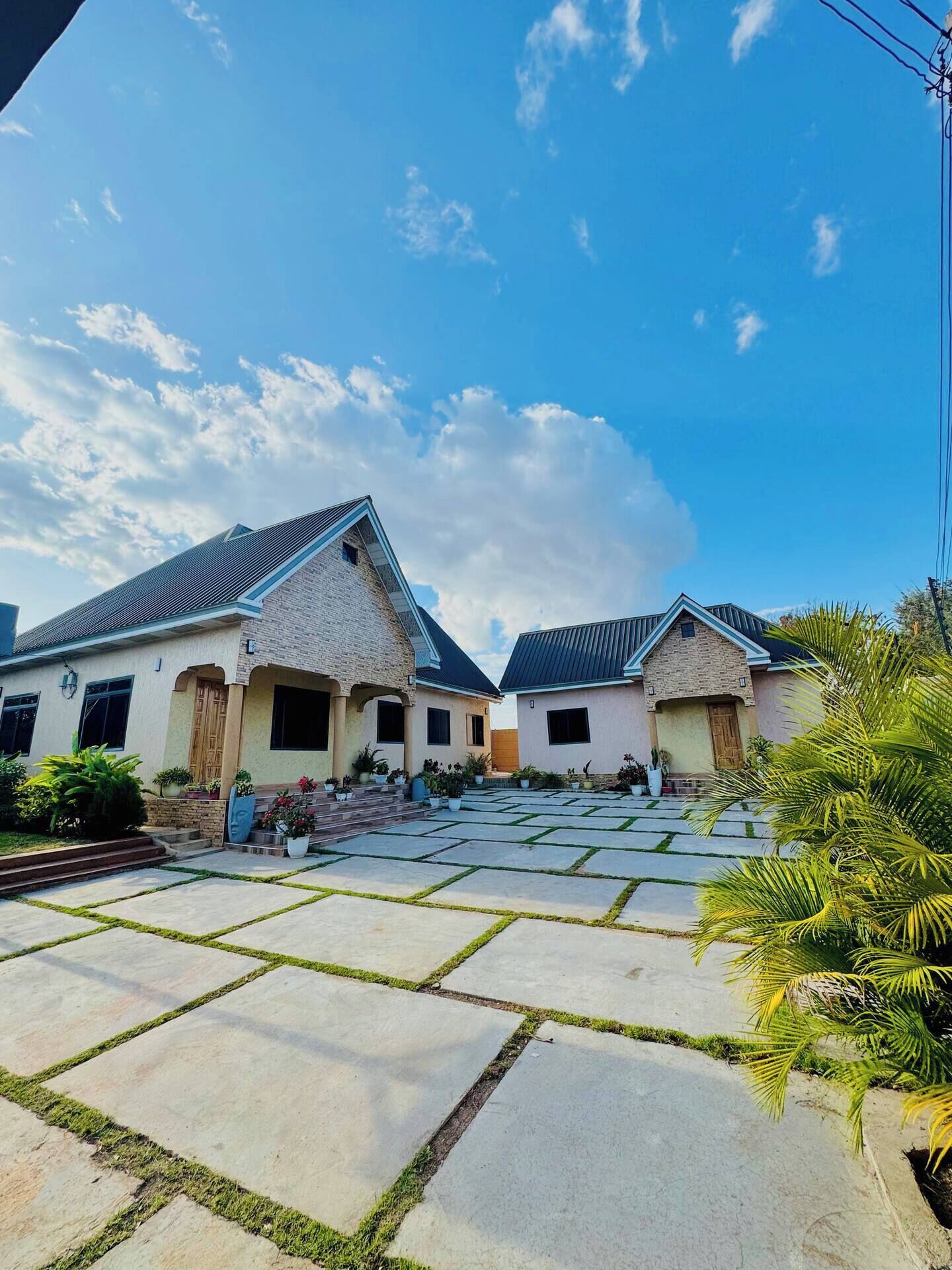 A residential property with two houses, a paved driveway, and a clear sky.