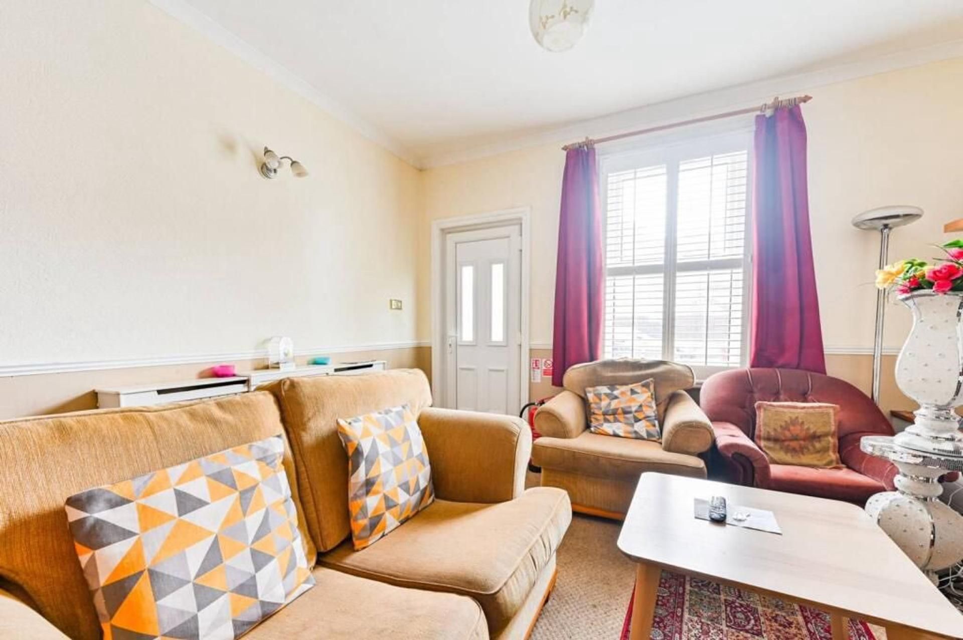 A living room with a beige sofa, a red armchair, and a coffee table.