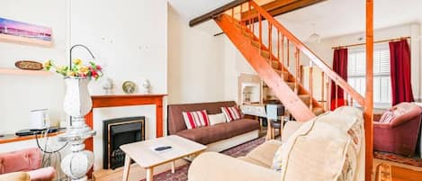 A living room with a fireplace, a sofa, a coffee table, and a staircase.