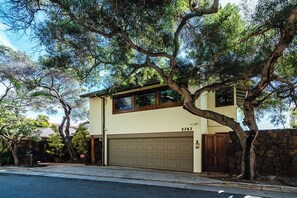 A two-story house with a garage, surrounded by trees. - Diamond Head Tranquility: 4BR Ocean View Home (Honolulu)