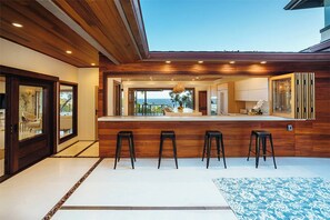 Eine moderne Küche mit Bar, Holzboden und Blick ins Freie.