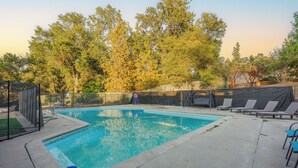 A rectangular swimming pool with a surrounding deck, a fenced area, and lounge chairs.