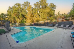 A rectangular swimming pool with a surrounding deck, a fenced area, and lounge chairs.