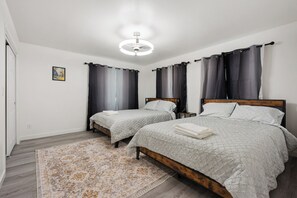 Une chambre avec deux lits, une tête de lit en bois, un luminaire au plafond et un tapis à motifs.