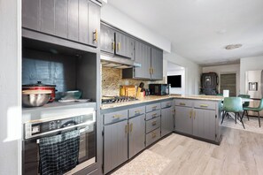 Une cuisine moderne avec des meubles gris, des appareils en acier inoxydable et un îlot central.