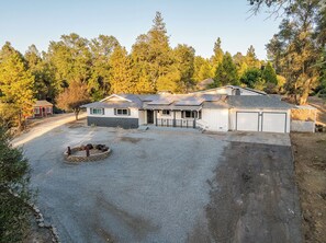 A two-story house with a gravel driveway and a fire pit in the front yard. - Yosemite Gateway Oasis - A Spacious 7 Bedroom house with pool (Oakhurst)
