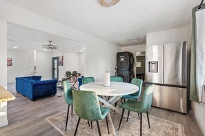 A modern kitchen with a stainless steel refrigerator, a dining table with chairs, and a blue sofa in the living area. - Yosemite Gateway Oasis - A Spacious 7 Bedroom house with pool (Oakhurst)
