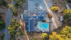 A residential property with a swimming pool, solar panels, and a fenced yard.
