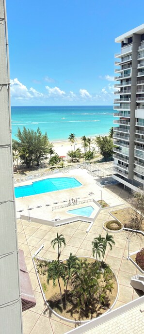 Un hotel con piscina, vista sulla spiaggia e palme.