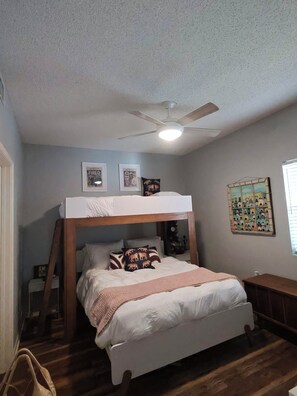 A bedroom with a bunk bed, a ceiling fan, framed pictures on the wall, and a small bedside table. - Lovely 2-bedroom condo with AC in Fort Walton Beach (Fort Walton Beach)