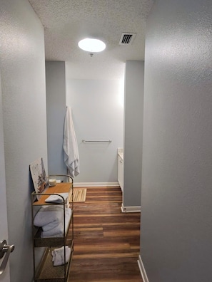 A narrow hallway with a wooden floor, a towel rack, and a small table with a candle. - Lovely 2-bedroom condo with AC in Fort Walton Beach (Fort Walton Beach)