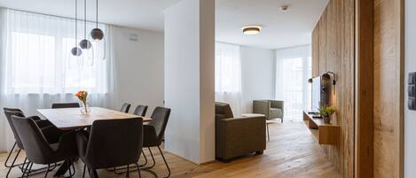 A modern interior with a dining area, sofas, and a wooden accent wall.