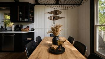 Een moderne keuken met een houten eettafel, zwarte stoelen en een bijzondere hanglamp.