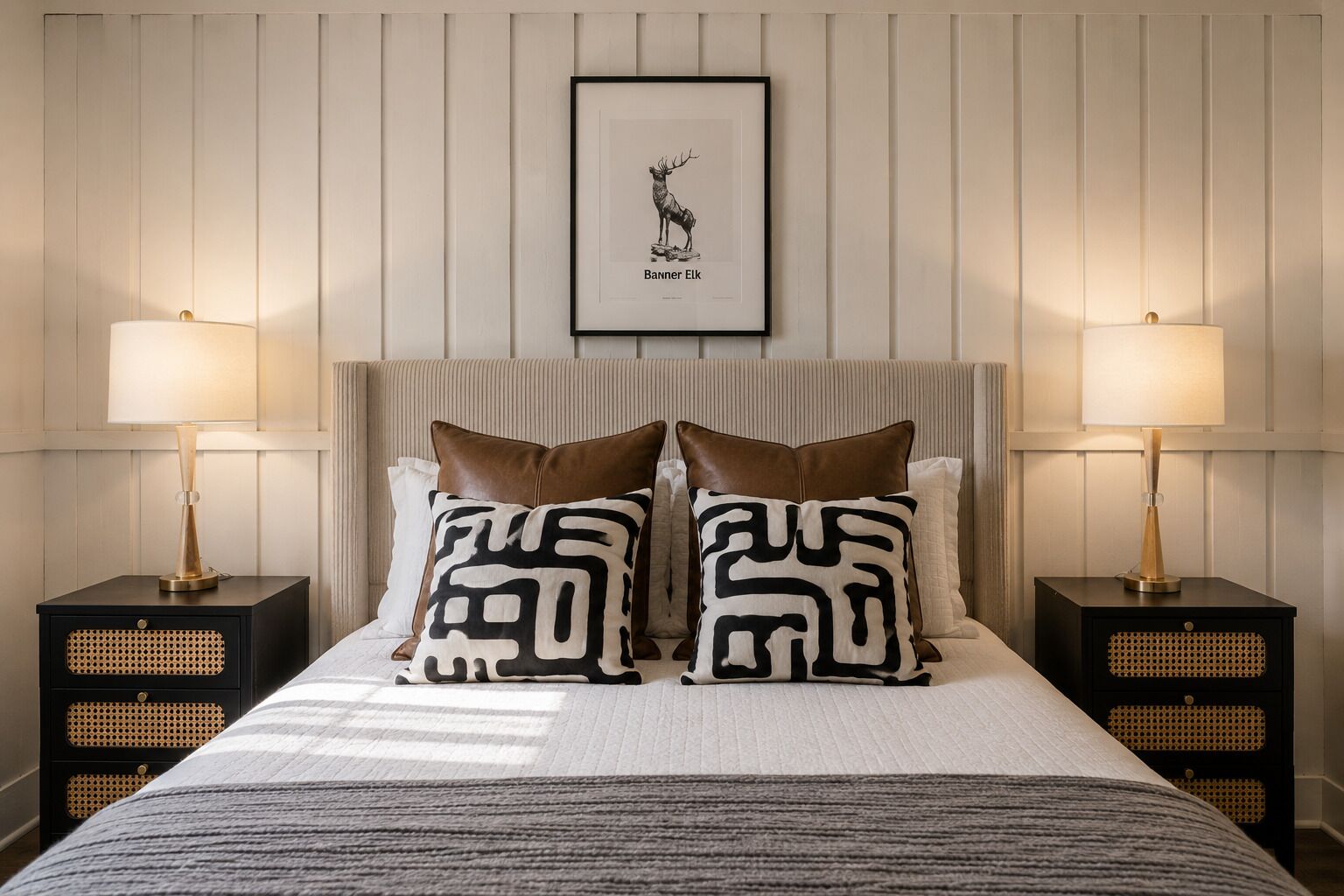 A bed with two pillows, a framed picture above, and two bedside tables with lamps.