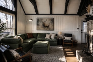 A cozy living room with a sectional sofa, a fireplace, and a large painting of a deer.