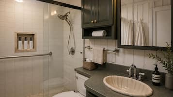 Een moderne badkamer met douche, toilet, wastafel en een spiegel.