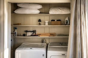 A laundry room with a washing machine, dryer, shelves with laundry supplies, and a basket labeled 'LOST SOCKS.' - 4-bedroom cabin with hot tub, firepit, kids loft, pet friendly. (Beech Mountain)