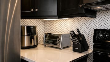 A kitchen with a stainless steel refrigerator, a toaster, and a knife block on the counter.