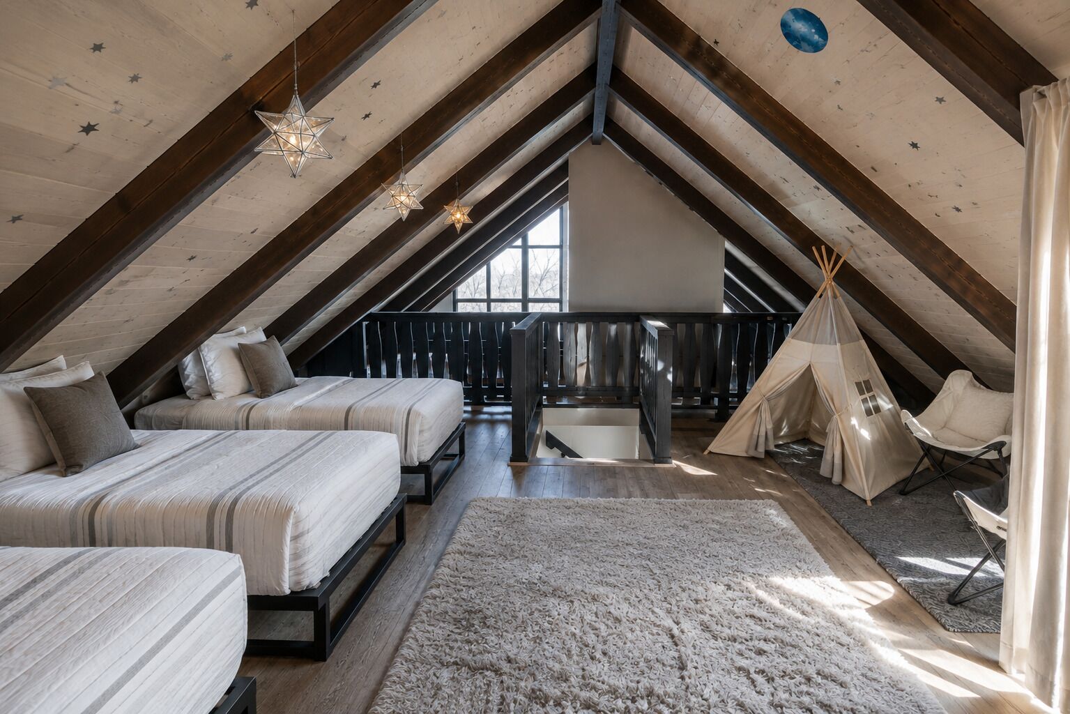 A cozy attic bedroom with two beds, a large window, a wooden ceiling, and a teepee tent.