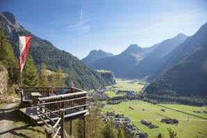 A mountain lodge with a wooden deck and a flag, overlooking a valley with houses and fields. - Holiday Apartment With Wellness Area (Laengenfeld)