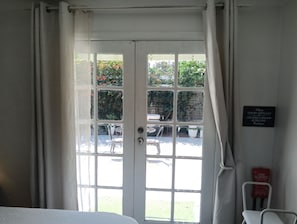 Een kamer met een witte deur die uitkomt op een buitenruimte met een tafel en stoelen. Op de muur hangt een bord met instructies voor gasten.
