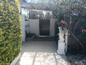 Een omheind toegangspunt met een stenen plantenbak, een gesloten metalen poort en een standbeeld.