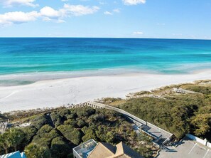 Une plage avec une promenade en bois qui mène à un bâtiment doté d’une piscine.