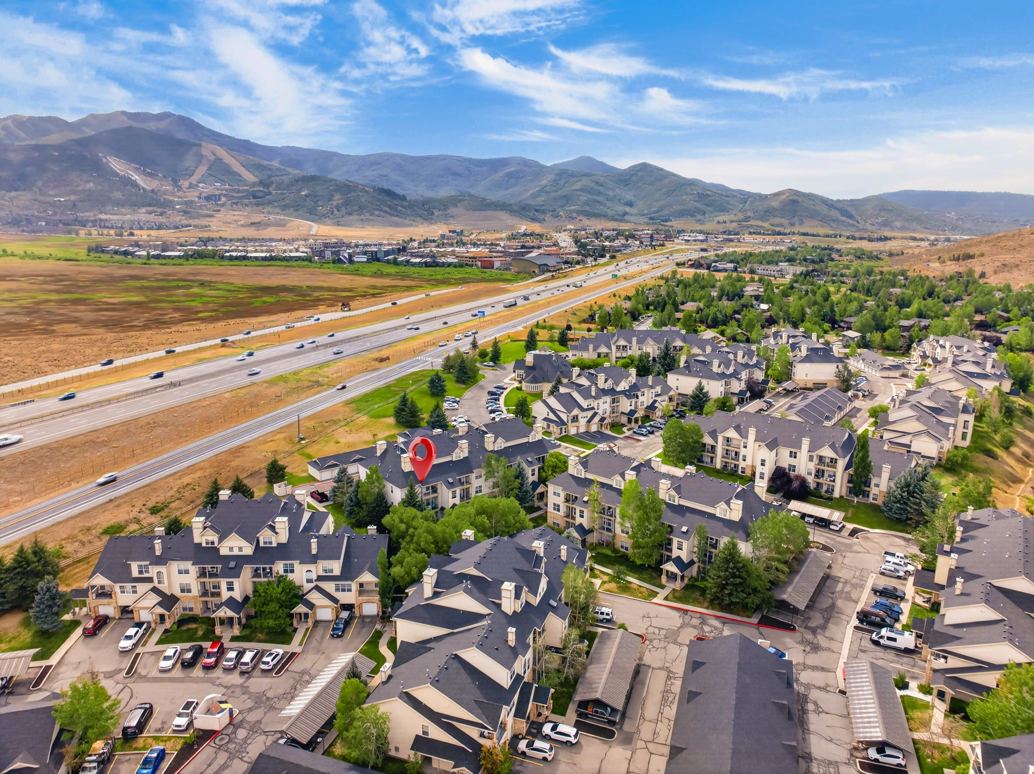A residential area with multiple-story houses, a highway, and a mountainous backdrop.