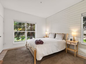 A bedroom with a large bed, two bedside lamps, a nightstand, and a view of greenery through a window. - Cute Updated 1BR Condo in Park City, 30 Night Min (Park City)