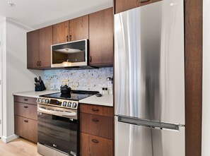 A modern kitchen with wooden cabinets, a stainless steel refrigerator, an LG oven, and a microwave. - Cute Updated 1BR Condo in Park City, 30 Night Min (Park City)