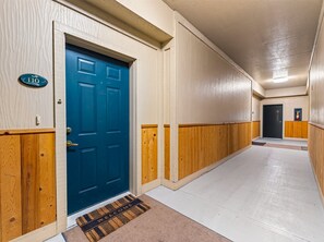 A hallway with a blue door, a welcome mat, and a sign with the number 110. - Cute Updated 1BR Condo in Park City, 30 Night Min (Park City)