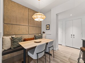 A modern kitchen with a wooden wall panel, a dining table with chairs, and a pendant light. - Cute Updated 1BR Condo in Park City, 30 Night Min (Park City)
