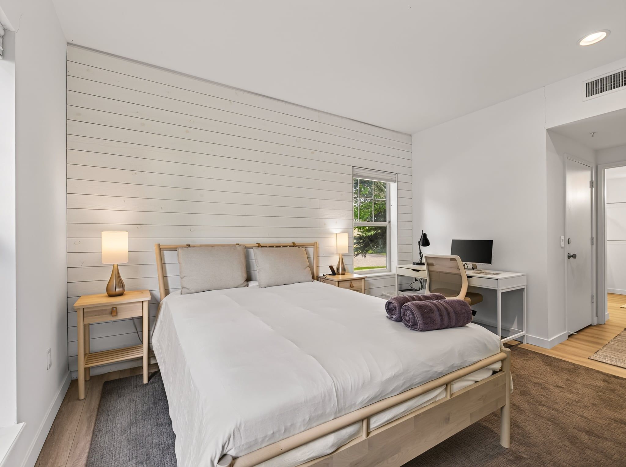 Ein Schlafzimmer mit einem Bett, Nachttischen, einem Schreibtisch und einem Sessel.